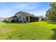 Sprawling backyard with lush green grass, mature trees, and a view of the house with a screened patio at 2607 Stanmore Ct, Orlando, FL 32817