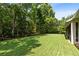 Expansive backyard with lush green grass and mature trees, with a view of the house and screened porch at 2607 Stanmore Ct, Orlando, FL 32817
