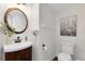 This half bath showcases a white toilet, wooden vanity, round mirror, and modern decorative features at 2607 Stanmore Ct, Orlando, FL 32817