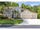 A well-manicured two-story home featuring a three-car garage, arched entryway, and lush landscaping at 2607 Stanmore Ct, Orlando, FL 32817