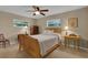 Sunlit bedroom featuring carpeted floors, ceiling fan, and two windows offering views of the surrounding yard at 303 S Sweetwater Blvd, Longwood, FL 32779