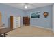 Cozy bedroom with light blue walls, neutral carpet, and a window with tree views at 303 S Sweetwater Blvd, Longwood, FL 32779