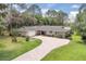 Charming ranch-style home with brick circular drive, lush lawn, mature trees and stone accents at 303 S Sweetwater Blvd, Longwood, FL 32779
