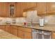 Close-up of the kitchen, featuring granite countertops, stainless steel dishwasher and sink, and tile backsplash at 303 S Sweetwater Blvd, Longwood, FL 32779