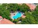 Aerial view of a resort-style pool area with lounge chairs, umbrellas, mature trees, and vibrant landscaping at 3112 Seaview Castle Dr, Kissimmee, FL 34746