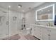 Bright bathroom featuring marble tile, glass shower door, double vanity, and a large, illuminated mirror at 325 Aldridge Ln, Davenport, FL 33897