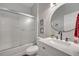 Well-lit bathroom showcasing a glass-enclosed tub-shower, round mirror, and modern vanity at 325 Aldridge Ln, Davenport, FL 33897