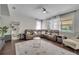Bright living room with sectional sofa, open shelving, and large windows with sheer curtains at 325 Aldridge Ln, Davenport, FL 33897