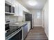 Galley kitchen featuring stainless steel appliances, granite countertops, white cabinets and luxury vinyl flooring at 4226 Kelly Miller Ct, Orlando, FL 32811