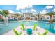 View of a community pool, with lounge chairs, tables, palm trees and an attached building with covered outdoor seating at 4441 Ganesha Loop, Kissimmee, FL 34746
