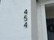 Close up of house numbers 454 affixed to a white stucco wall, next to a gray door at 454 Captiva Dr, Davenport, FL 33896