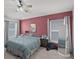 Cozy bedroom featuring a red accent wall, ceiling fan and natural light from the windows at 503 Meadow Pointe Dr, Haines City, FL 33844