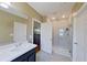Well-lit bathroom featuring a glass-enclosed shower, a single sink vanity, and neutral tiling at 5515 Windsong Oak Dr, Leesburg, FL 34748