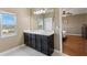 Bathroom featuring double sinks with dark cabinets and a window for natural light at 5515 Windsong Oak Dr, Leesburg, FL 34748