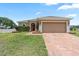 Inviting single-story home with a brick driveway, attached garage, and a neatly landscaped front yard at 5515 Windsong Oak Dr, Leesburg, FL 34748
