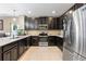 Modern kitchen with dark cabinetry, stainless steel appliances, granite countertops, and tile flooring at 5515 Windsong Oak Dr, Leesburg, FL 34748