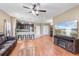 Open-concept living area with hardwood floors, a ceiling fan, and a view into the modern kitchen at 5515 Windsong Oak Dr, Leesburg, FL 34748