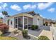 Side view of a cozy home featuring a screened-in porch, manicured landscaping, and a two-car garage at 6223 Atkinson Ln, The Villages, FL 32163