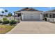 Exterior view of a well-maintained home with a two-car garage and lush landscaping along the driveway at 6223 Atkinson Ln, The Villages, FL 32163