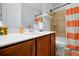 Bright bathroom with orange accents, a shower, a toilet and a vanity with storage at 634 Via Corso Ct, Kissimmee, FL 34759