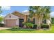 Charming single-story home featuring a stone facade, well-manicured lawn, and a mature palm tree at 634 Via Corso Ct, Kissimmee, FL 34759