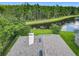 A lovely aerial view of home's roof and chimney backing to a pond and a line of tall trees at 9942 Sweetleaf St, Orlando, FL 32827