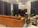 This living room features a brown leather couch, a large tv, and several plants to brighten up the space at 15708 Orange Harvest Loop, Winter Garden, FL 34787