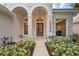 Elegant front entrance with decorative columns, a hanging light fixture, and landscaped garden beds at 1266 Saint Albans Loop, Lake Mary, FL 32746