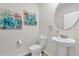 Elegant half-bathroom with a pedestal sink, round mirror, and stylish floral artwork at 1555 Dawnview Way, Kissimmee, FL 34744