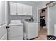 Well-lit laundry area showcasing side-by-side washer and dryer units and overhead storage cabinets at 16758 Ne 135Th Ave, Fort Mc Coy, FL 32134