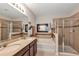 Bright bathroom featuring double sinks, soaking tub with decorative accent, and glass enclosed shower at 2426 Addison Creek Dr, Kissimmee, FL 34758
