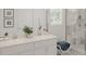 Bathroom features a double vanity, framed nautical prints, and a tiled glass shower at 2441 Spring Tune Aly, Kissimmee, FL 34744