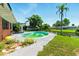 Backyard features a fenced in pool surrounded by green grass, tropical trees, and canal view at 2504 Caribbean Ct, Orlando, FL 32805