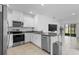 Modern kitchen with white cabinets, stainless steel appliances, granite countertops, and an open view to the living area at 3624 Sungrove Cir, Sanford, FL 32771