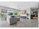 Bright living room with gray tile flooring, gray sofa, and large windows overlooking the landscaped backyard at 3865 W Stillwood Ln, Lake Mary, FL 32746