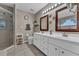 Bathroom featuring double sinks with white cabinets, two framed mirrors, and glass-enclosed shower at 445 Oakland Park Blvd, Port Orange, FL 32127