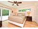 Bright bedroom with a ceiling fan, sliding glass door, light hardwood floors, and two bedside tables with lamps at 507 N Peninsula Ave, New Smyrna Beach, FL 32169