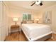 Bright bedroom with light hardwood floors, ceiling fan, bedside lamps, a painting, and closet with sliding doors at 507 N Peninsula Ave, New Smyrna Beach, FL 32169