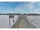 Long wooden dock provides access to waterfront properties under a partly cloudy blue sky at 507 N Peninsula Ave, New Smyrna Beach, FL 32169