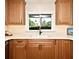 Sunlit kitchen features plentiful wood cabinets, granite countertops, updated sink, and a view of the outdoors at 507 N Peninsula Ave, New Smyrna Beach, FL 32169