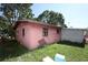 Exterior view of a pink brick house with fenced yard and overgrown grass at 5262 Lescot Ln, Orlando, FL 32811