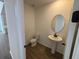 Half-bath features a pedestal sink, round mirror, and modern fixtures at 710 Junonia Blvd, New Smyrna Beach, FL 32168