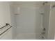 Bright bathroom featuring a tiled tub with mounted shower head and convenient wall shelves at 715 Auburn Grove Ct, Auburndale, FL 33823