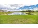 Scenic view of the neighborhood pond, surrounded by lush green grass and open sky at 715 Auburn Grove Ct, Auburndale, FL 33823