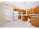 Well-lit kitchen featuring white appliances, wood cabinets, granite countertops, and tile flooring at 7263 Winding Lake Cir, Oviedo, FL 32765