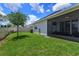 Grassy backyard with a tree and partial fence is adjacent to screened lanai at 1132 Sugarwood St, Davenport, FL 33837