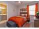 Comfortable bedroom featuring a wooden bed frame, warm colored bedding, and bright orange curtains at 1132 Sugarwood St, Davenport, FL 33837