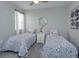 Bright bedroom featuring twin beds with patterned bedding, a mirrored wall accent, and a window with sheer curtains at 1132 Sugarwood St, Davenport, FL 33837