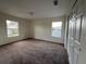 Neutral bedroom features brown carpet, two windows and a white closet door at 1325 Bella Coola Dr, Orlando, FL 32828