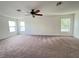 This bonus room is spacious with neutral walls, carpeting, a ceiling fan, and lots of natural light from three windows at 1325 Bella Coola Dr, Orlando, FL 32828